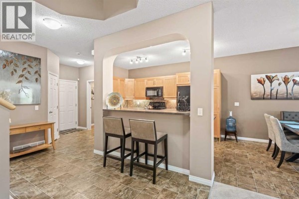 Interior view of a home showing a kitchen pass-through with bar stools, and dining room area. - 52 Copperfield Close Se, Calgary