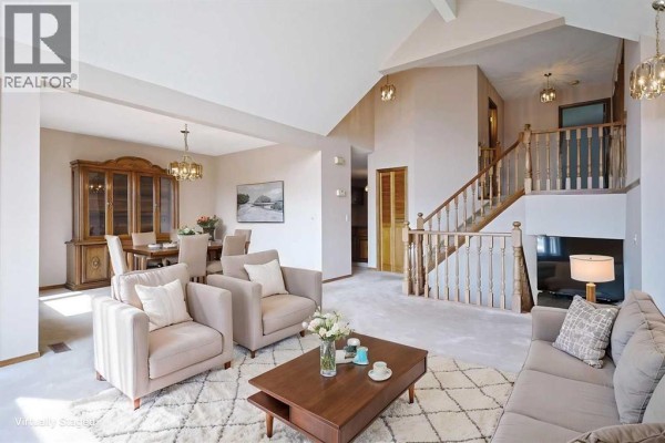 Living and dining room with vaulted ceilings, carpeted floors, and a staircase leading upstairs. - 52 Edgeland Road Nw, Calgary