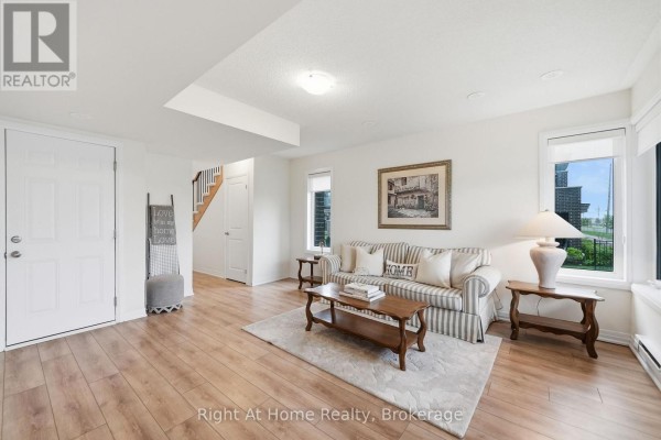 Living room with striped sofa, wooden coffee table, and large windows. - 52 Emmas Way, Whitby