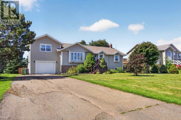 Side view of the light gray bungalow showing the driveway and attached garage. - 52 Hallie Drive, Summerside