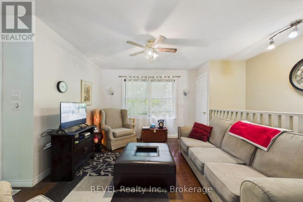 A living room with a beige sofa, armchair, dark wood coffee table, and television on a dark media stand. - 52 Orr Road, Huntsville