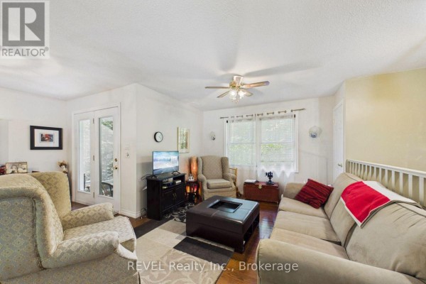 A spacious living room featuring a sectional sofa, armchair, television, and French doors leading outside. - 52 Orr Road, Huntsville