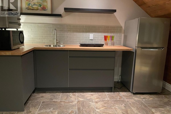 Compact kitchenette with grey cabinetry, wooden countertop, stainless steel refrigerator, and microwave. - 52 Pine Ridge Trail, Oro Medonte
