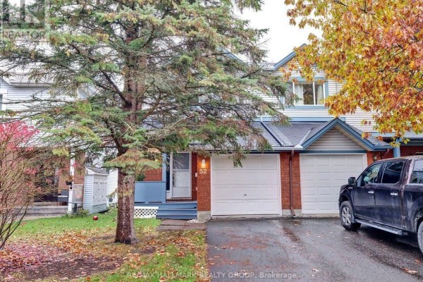 Front exterior of townhouse with brick and vinyl siding, a garage door, and a parked black pickup truck. - 52 Piper Crescent, Ottawa