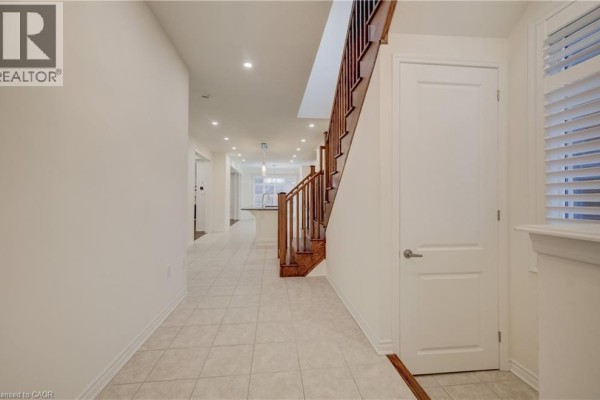 Interior view of a foyer with a staircase, beige tiled floor, and white walls. - 52 Pointer Street, Cambridge