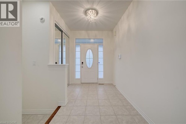 Interior view of a foyer with a front door, sidelight windows, and beige tiled floor. - 52 Pointer Street, Cambridge