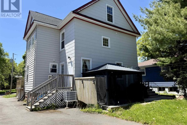 Rear exterior of a light grey house with a wooden deck, screened gazebo, and outdoor AC unit. - 52 Rupert Street, Amherst