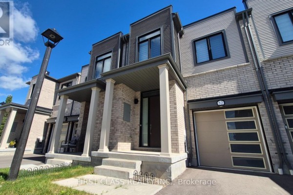 Front view of a modern townhouse with beige brick, grey siding, and a covered porch with columns. - 52 Sorbara Way, Whitby