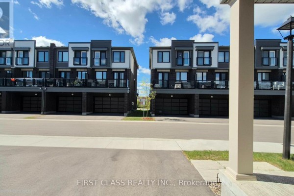 View down a street showing identical townhouses with balconies and garages on either side. - 52 Sorbara Way, Whitby