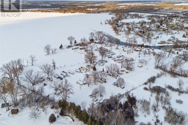 Aerial view of a snowy landscape with residential units, trees, and a river flowing nearby. - 52 Sunset Lagoon Drive, Prince Edward County