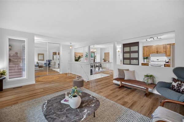 Living and dining area with hardwood floors, white walls, and a view of the kitchen through a cutout. - 52 Trowbridge Bay, Winnipeg