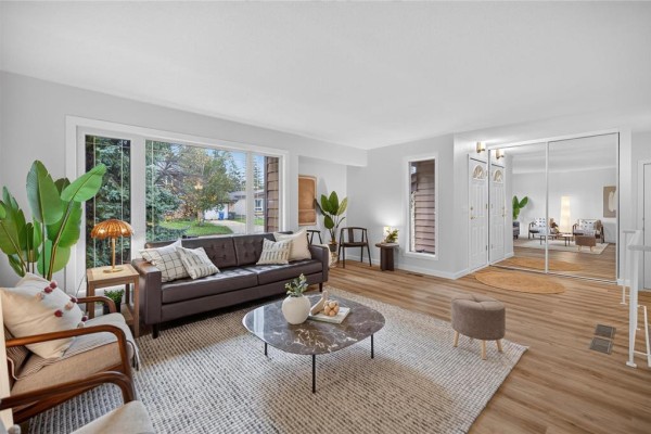 Living room with a sofa, coffee table, and mirrored closet doors reflecting the space. - 52 Trowbridge Bay, Winnipeg