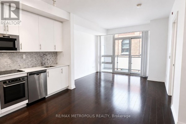Kitchen with white cabinets, stainless steel appliances, and dark wood floors. - 520 - 460 Adelaide Street E, Toronto