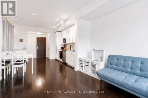 Kitchen with white cabinets, backsplash, stainless steel appliances, and dark floors. - 520 - 460 Adelaide Street E, Toronto