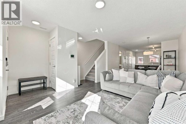Living room with grey sectional sofa, rug, and staircase leading upstairs. - 520 Auburn Bay Circle Se, Calgary
