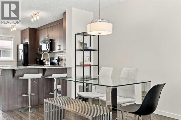 Dining area with glass table, chairs, bench, and kitchen island. - 520 Auburn Bay Circle Se, Calgary