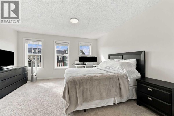 Bedroom with king-size bed, dresser, nightstand, and three windows. - 520 Auburn Bay Circle Se, Calgary