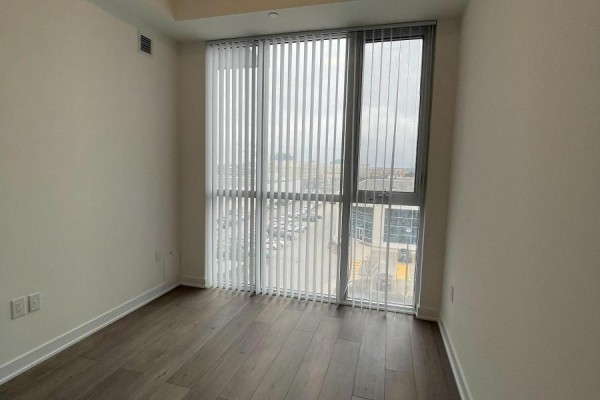 Empty room with vertical blinds on a large window and wood plank flooring. - 521 - 10 Honeycrisp Crescent, Vaughan