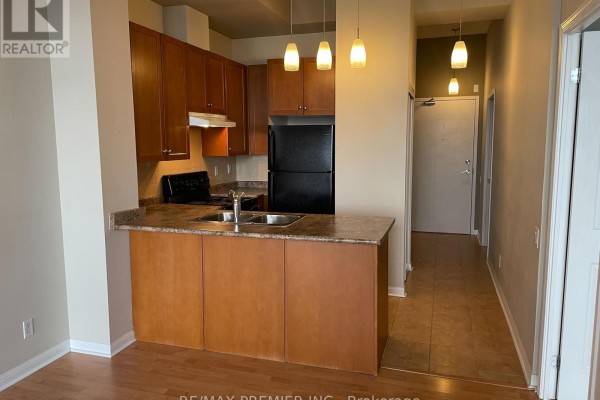Apartment kitchen with wood cabinets, laminate countertops, black appliances, and a hallway. - 521 - 1600 Keele Street, Toronto
