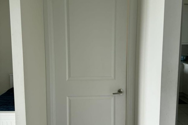 Interior view of a white door with a silver handle in a hallway with neutral walls. - 521 - 50 Thomas Riley Road, Toronto