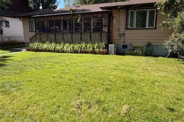 Backyard view of the house showing a screened-in porch with a wooden deck and green lawn. - 521 17th Street, Brandon