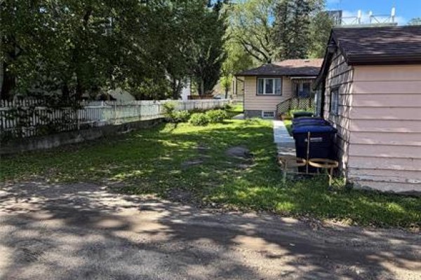 Side view of the house with a white vinyl fence bordering a grassy yard and driveway. - 521 17th Street, Brandon