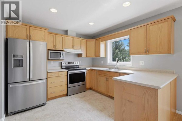 Kitchen with light wood cabinets, stainless steel appliances, and a U-shaped counter. - 521 Partridge Crescent, Pelican Point
