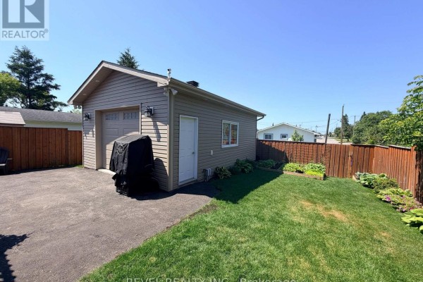 Modern kitchen with an island, granite countertops, and stainless steel appliances, open to dining area. - 521 Pine Street N, Timmins
