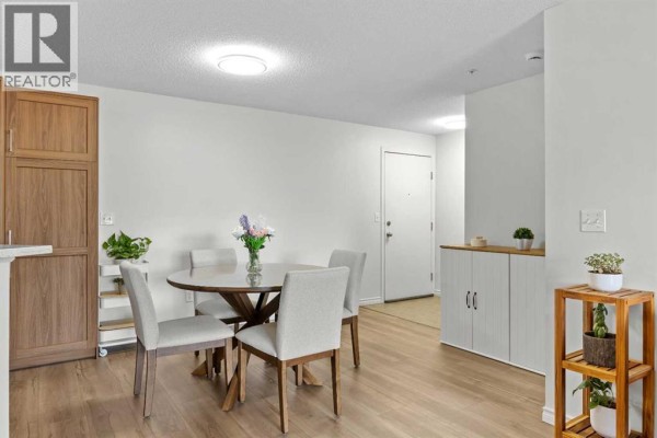 Dining area with a round table, four chairs, and light wood laminate flooring. - 5210, 16969 24 Street Sw, Calgary