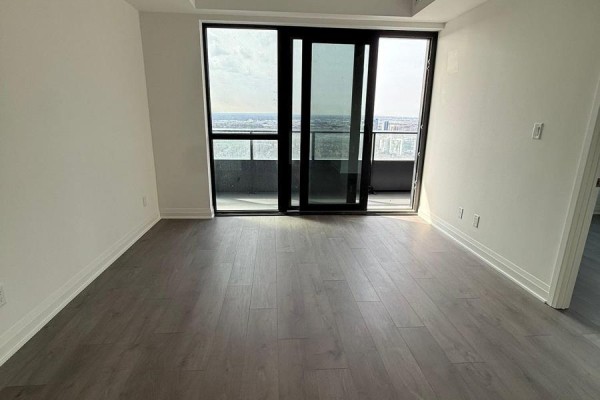 Empty living area with large sliding balcony doors and city view. - 5210 - 4015 The Exchange, Mississauga