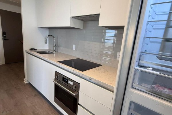 Kitchen with white cabinetry, stainless steel appliances, grey backsplash, and open refrigerator. - 5210 - 4015 The Exchange, Mississauga