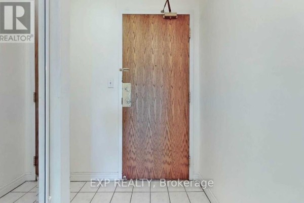 Hallway with a wooden door and white walls, tiled floor. - 522 - 1700 Eglinton Avenue E, Toronto