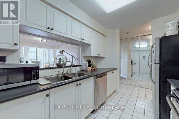 Kitchen with white cabinets, black countertops, stainless steel appliances, and tile flooring. - 522 - 1700 Eglinton Avenue E, Toronto