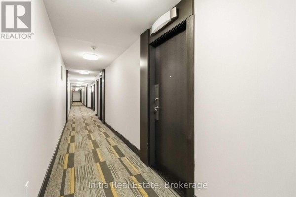 Long building hallway with patterned carpet, white walls, and numerous doors. - 522 - 55 Ann O'reilly Ann O'reilly Road, Toronto