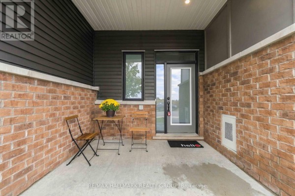 Covered front porch with brick walls, glass door, and two small chairs with a table. - 522 Culdaff Road, Ottawa