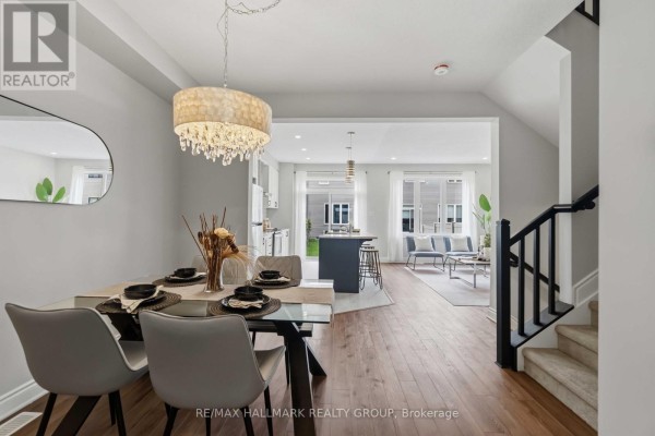 Open-concept main floor showing dining area, island kitchen, and living room with large windows. - 522 Culdaff Road, Ottawa