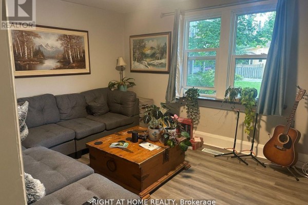 Living room with a large sectional sofa, a wooden trunk coffee table, and bay windows. - 522 Kingston Road W, Ajax