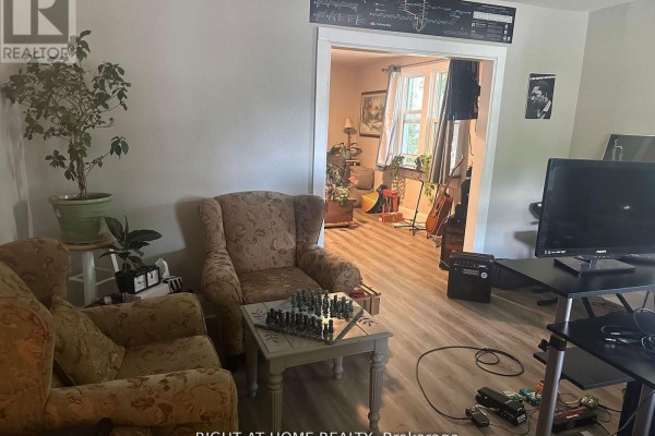 Interior view of a living area with armchairs, a chess set, and a doorway to another room. - 522 Kingston Road W, Ajax