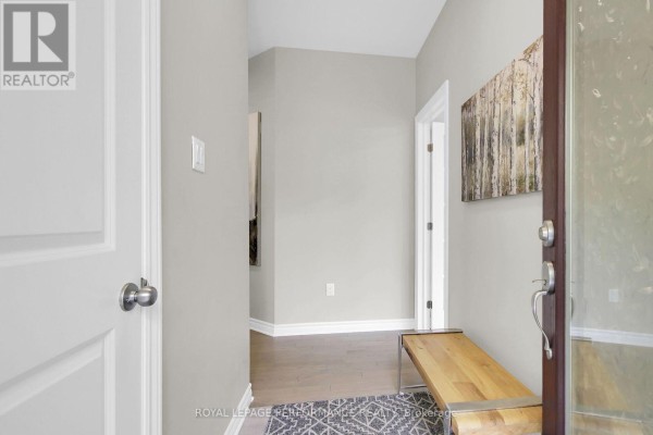 Interior foyer with light grey walls, a wooden bench, and artwork. - 522 Silverbell Crescent, Ottawa