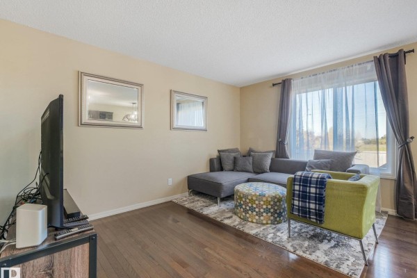 Living room with grey sectional sofa, green accent chair, ottoman, and television on a stand. - 5220 1a Av Sw, Edmonton