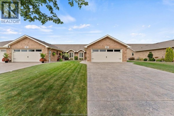 Front view of a brick townhouse complex with two garage doors and manicured front lawns. - 523 Golfview, Amherstburg