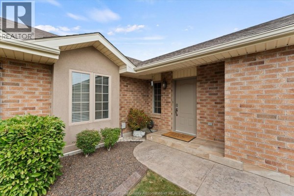 Entrance to a brick townhouse with a beige door, stone walkway, and landscaping. - 523 Golfview, Amherstburg