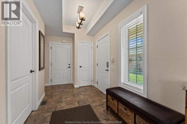 Interior entryway with beige walls, tiled floor, white doors, and a dark storage bench. - 523 Golfview, Amherstburg