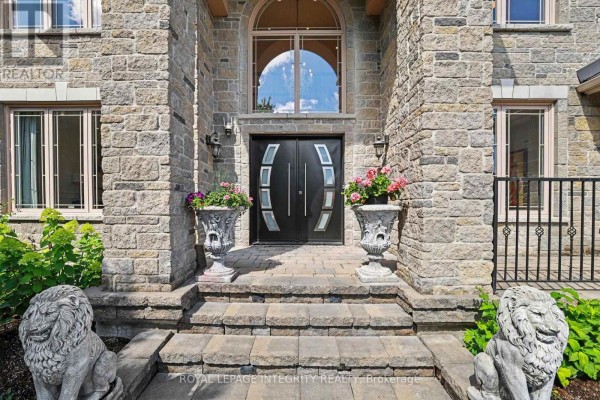 Double front doors with glass panels, flanked by stone lions and urns on stone steps. - 523 Kochar Drive, Ottawa