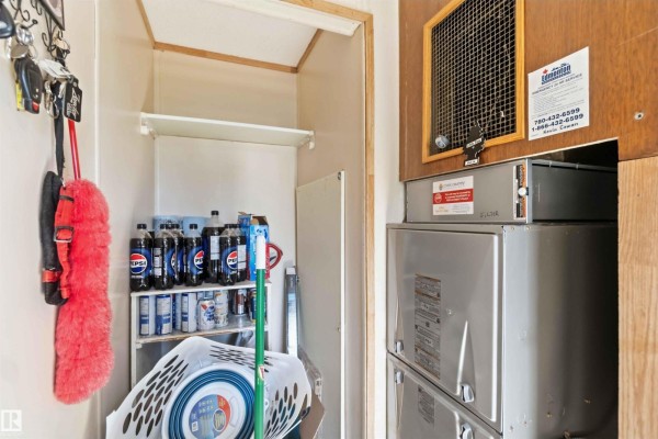 Utility closet with shelving, cleaning supplies, bottles of soda, and two large HVAC units. - 52315 Rge Road 273, Rural Parkland County