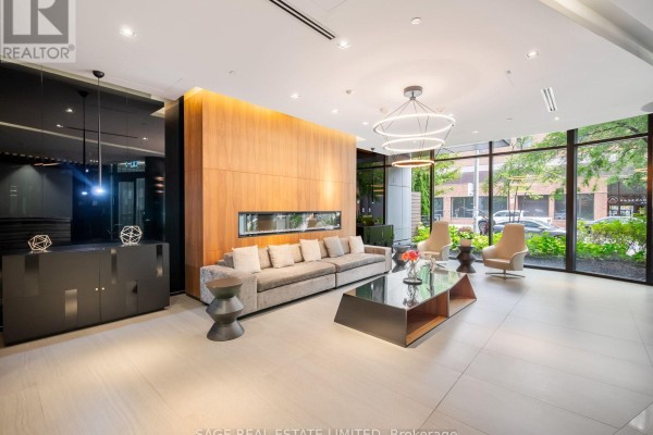 Building lobby with gray sofa, wood feature wall, fireplace, and modern light fixtures. - 524 - 38 Cameron Street, Toronto