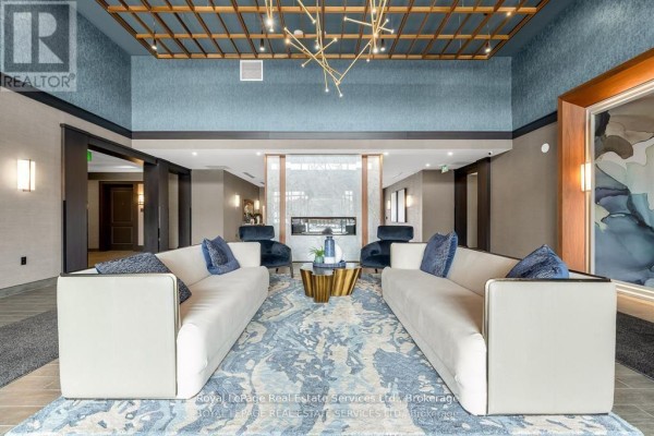 Luxurious apartment building lobby with white sofas, blue armchairs, and fireplace. - 524 - 460 Dundas Street E, Hamilton