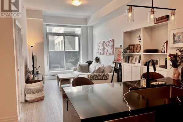 Living room area with white sofa, coffee table, and built-in bookshelves. - 524 - 460 Dundas Street E, Hamilton