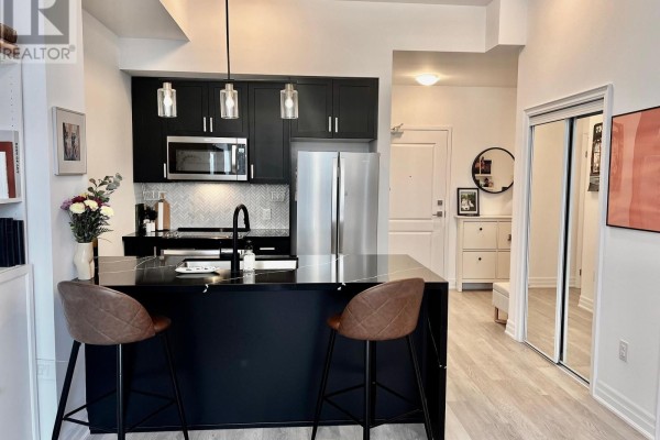 Modern kitchen with black cabinetry, stainless steel appliances, and island bar. - 524 - 460 Dundas Street E, Hamilton