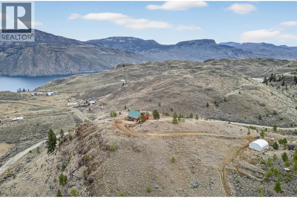 Expansive view of the property on a hillside with sparse vegetation and distant structures - 524 Deer Drive, Kamloops